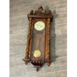 A Vienna walnut drop dial wall clock with Roman dial, spindle detail, decorative arch pediment,