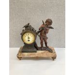 An Art Deco spelter and marble mantel clock, winged putto “Flute Enchanter” beside waisted clock,