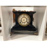 An early 20th Century black painted metal mantel clock, Roman dial, lion mask ring handles, gilt