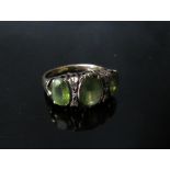 A 9ct gold ring with three oval peridots, the central stone flanked by three diamonds. Size N/O, 4.
