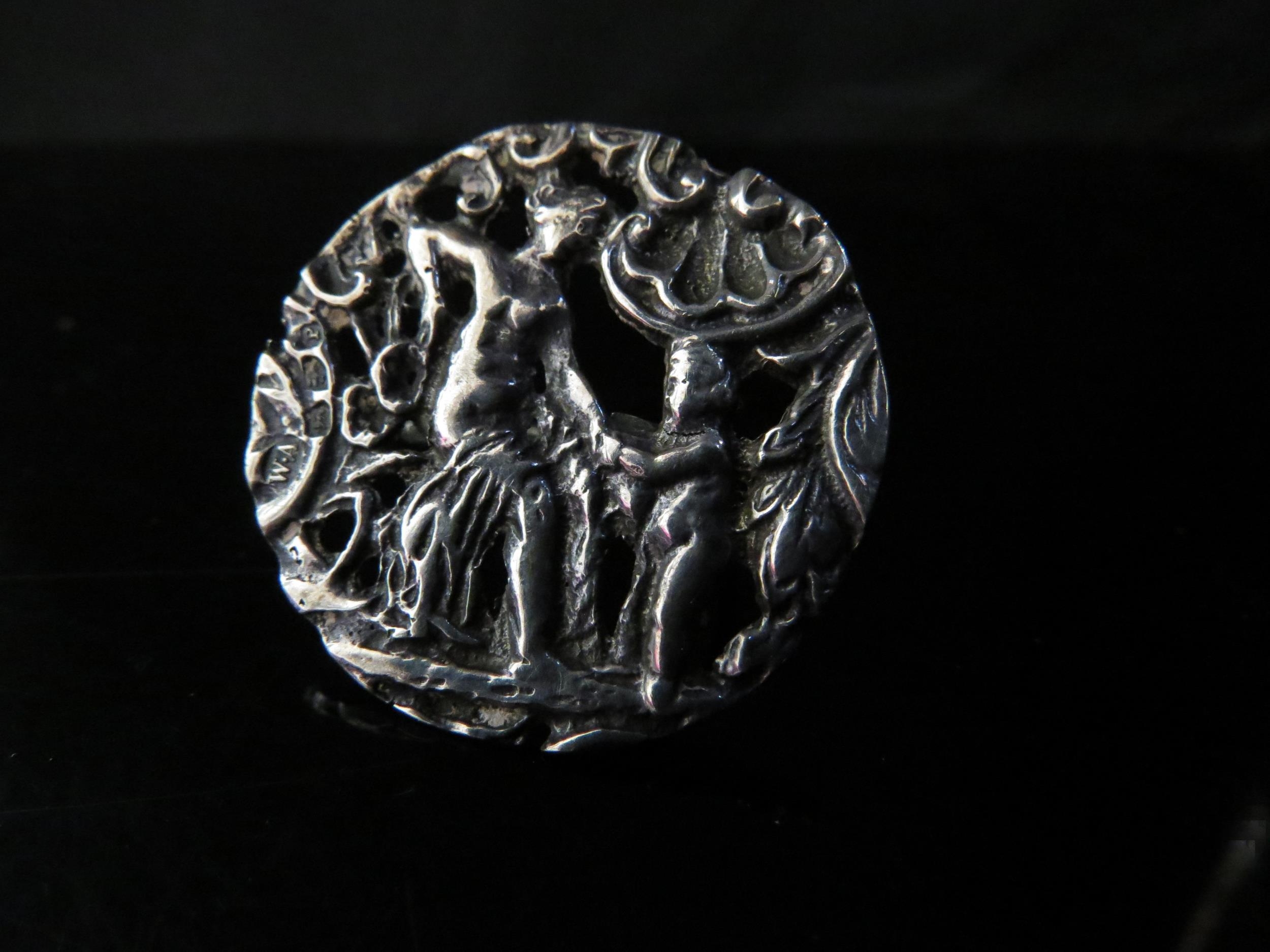 A silver ring made from a button depicting female and putto, 3.3cm diameter. Size N, 7.3g