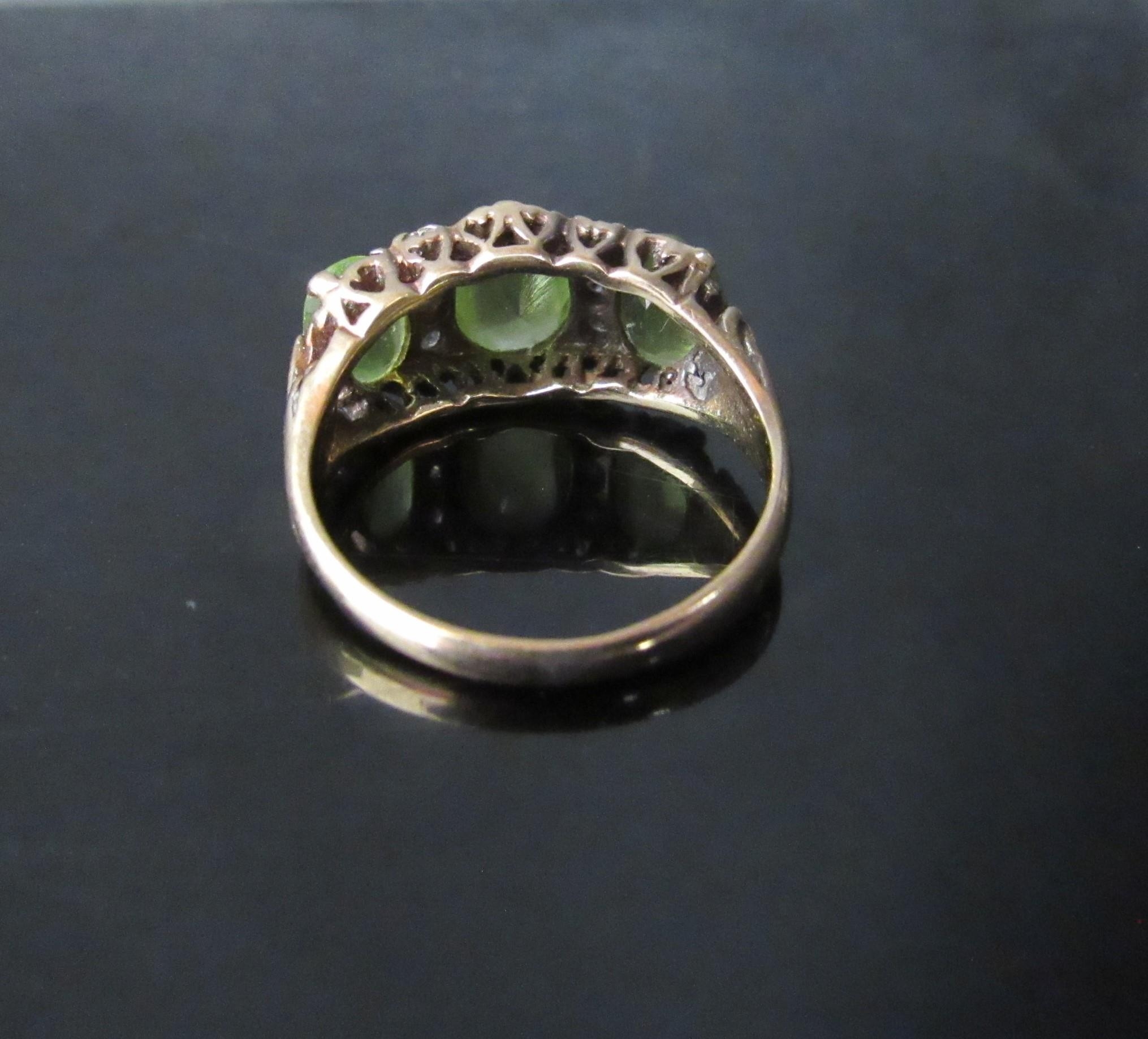 A 9ct gold ring with three oval peridots, the central stone flanked by three diamonds. Size N/O, 4. - Image 3 of 3