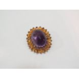 A brooch set with a large faceted amethyst surrounded by bright cut citrines forming a flower