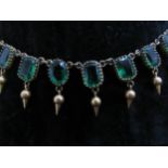 A riviere necklace set with emerald green paste stones each hung with pointed drop, gilt metal,