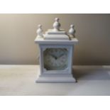 A modern white mantel clock with storage compartment