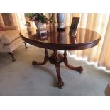 A Victorian mahogany loo table of oval form with four pillar support to quatraform scroll legged
