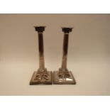 A pair of Georgian silver candlesticks of corinthian column form with swag and mask detail to