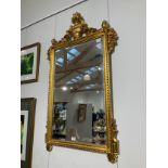 A modern gilt over mantel mirror with urn and swag detail, bevelled edge glass, 128cm x 75cm