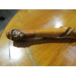 A knarled twisted wood walking cane with carved double ended mask of a man, 92cm long