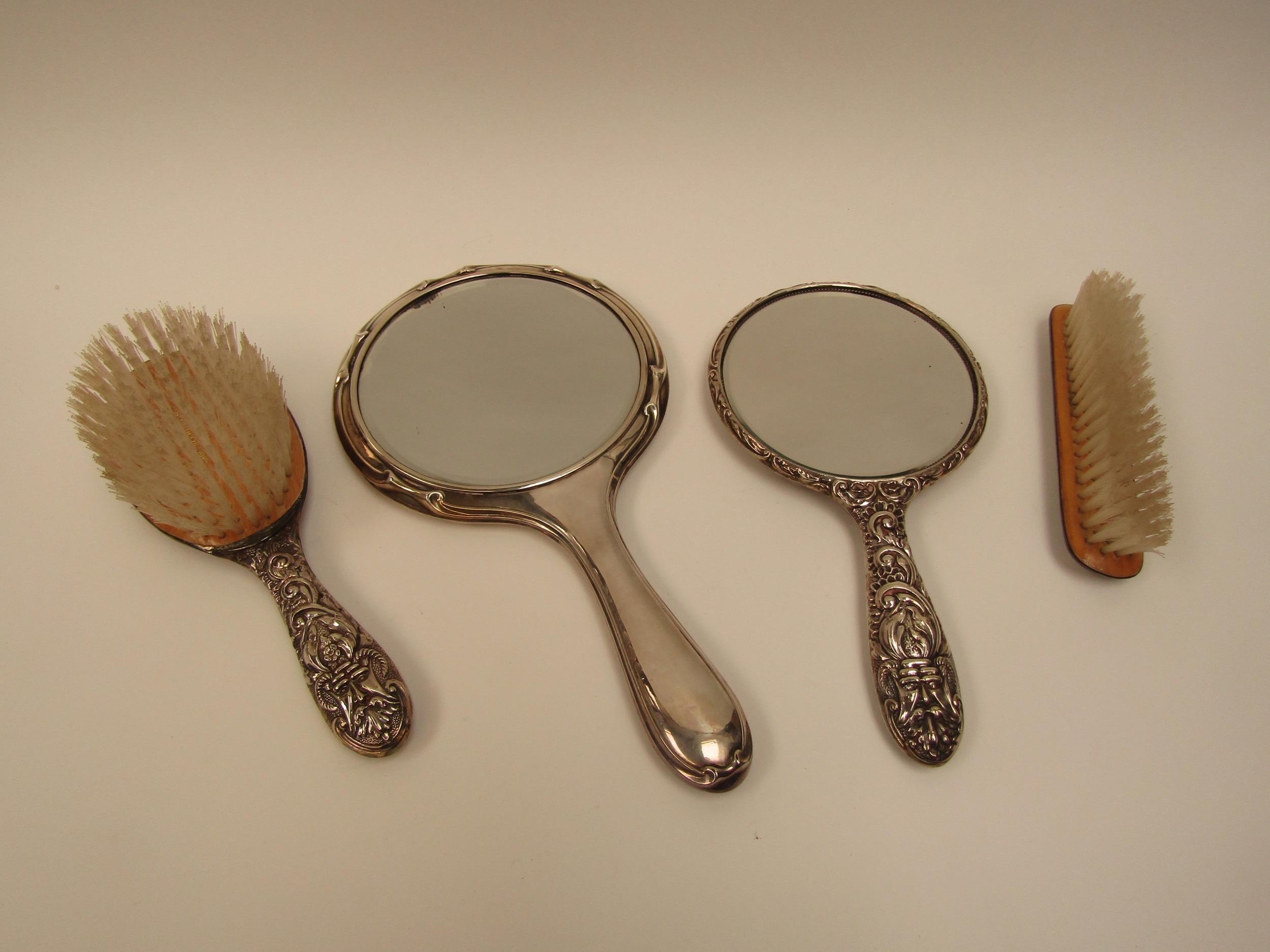 A silver three piece dressing table set and associated mirror (4)