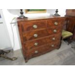 A Georgian mahogany two over three chest of drawers with oval plate handles, shaped apron, canted