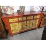 An Oriental painted sideboard of four drawers over four cupboard doors with still-life decoration of