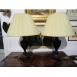 A pair of modern antiqued bronze effect metal brass form lamps with pleated cream shades, 67cm tall,