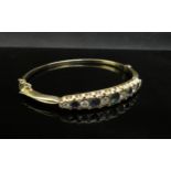 A gold stiff hinge bangle set with alternate sapphires and diamonds, 1ct approx diamond total,