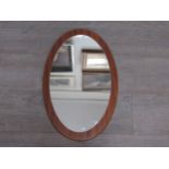 A Mid Century teak backed oval wall mirror. Overall size 57cm x 36cm