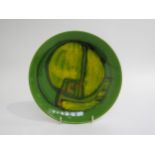 A Poole Pottery Delphis range plate in green glazes with ochre and orange. Marks to base and