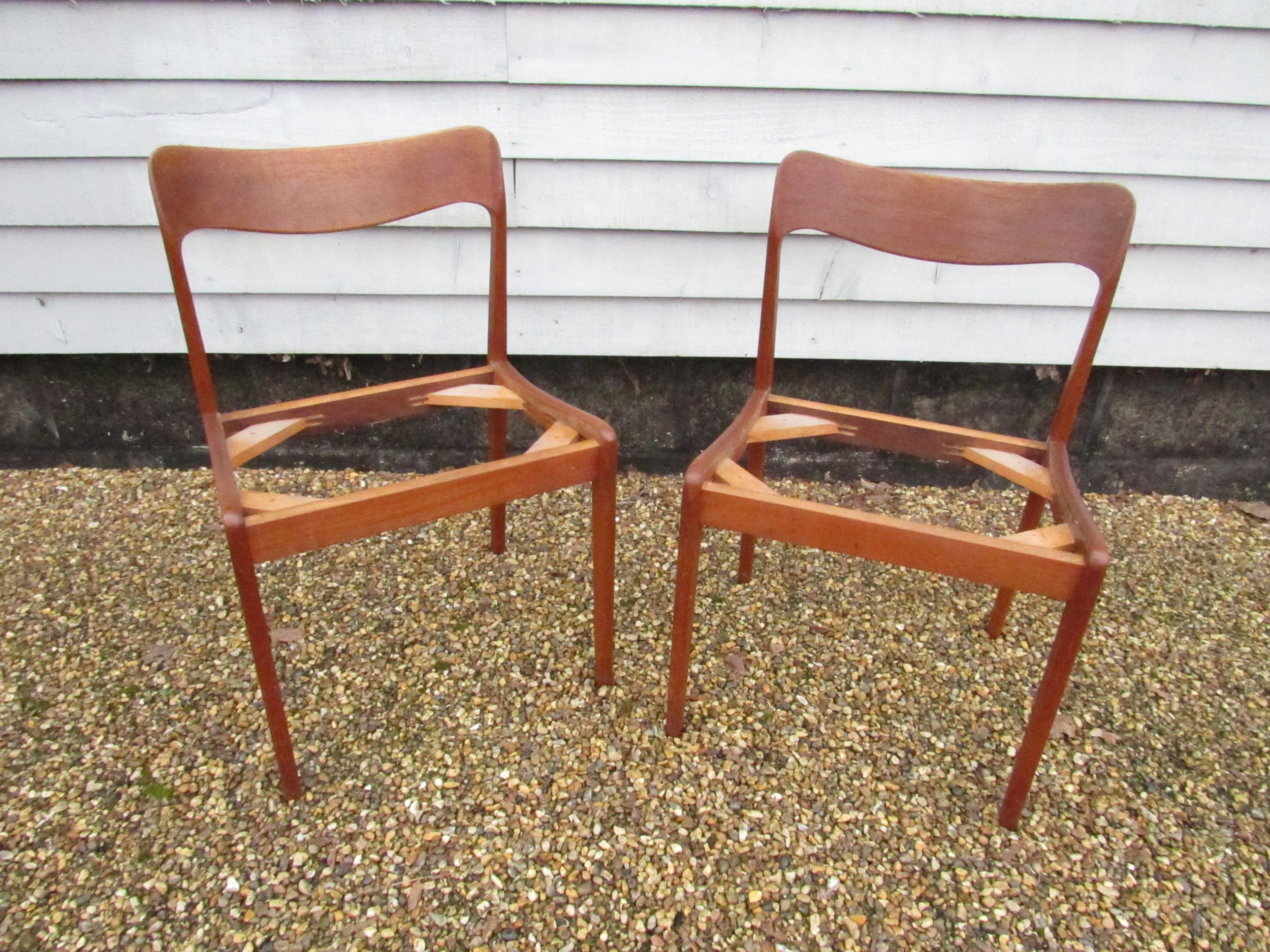 A pair of Danish teak dining chairs, seat pads removed as do not conform with current Fire Safety