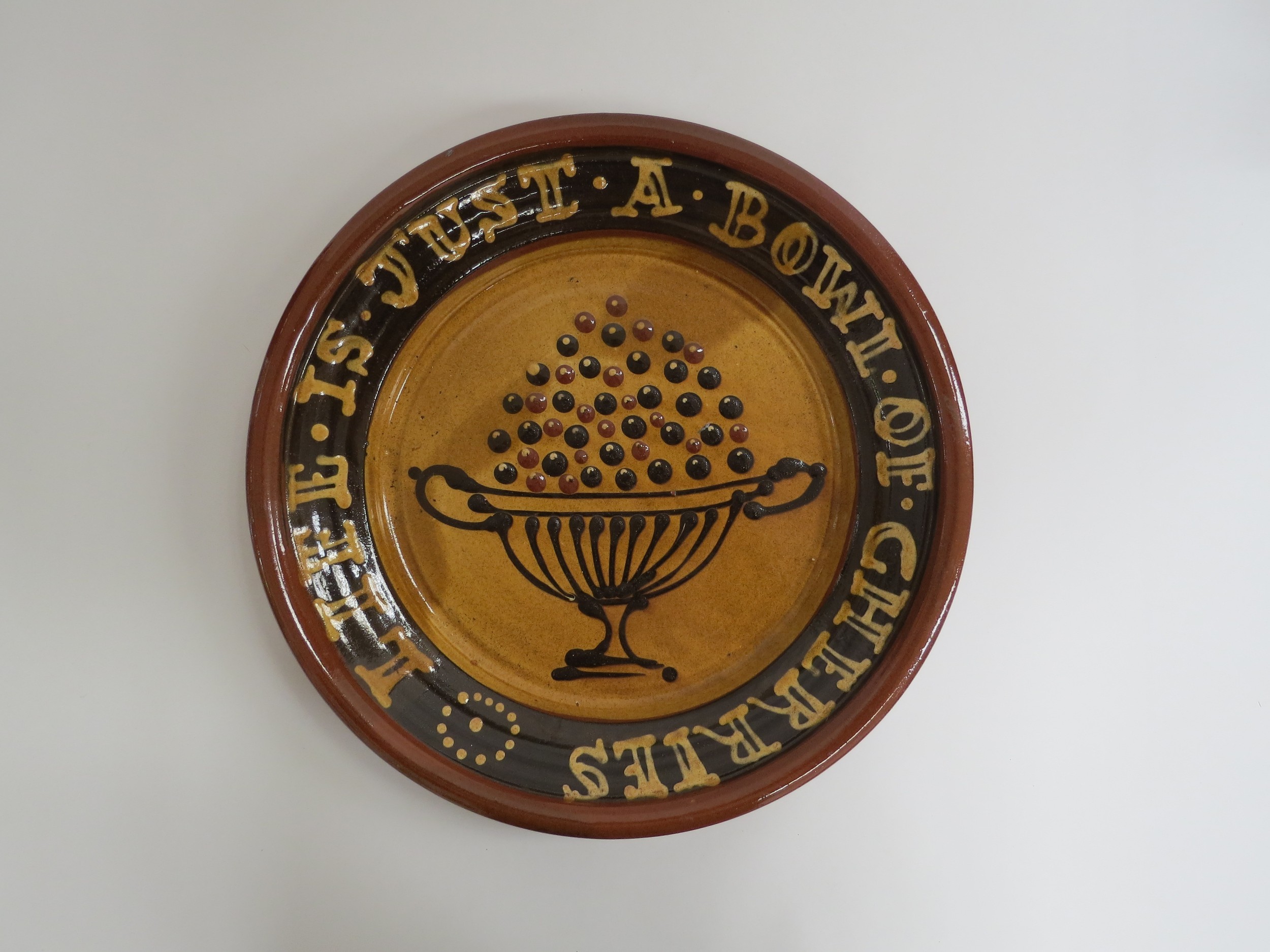 A Bredon Pottery slipware charger by Tony & Sue Davies, 'Life Is Just A Bowl Of Cherries'. Label