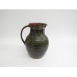 A Winchcombe Pottery tenmoku glazed stoneware jug. Impressed pottery seal. 21cm high