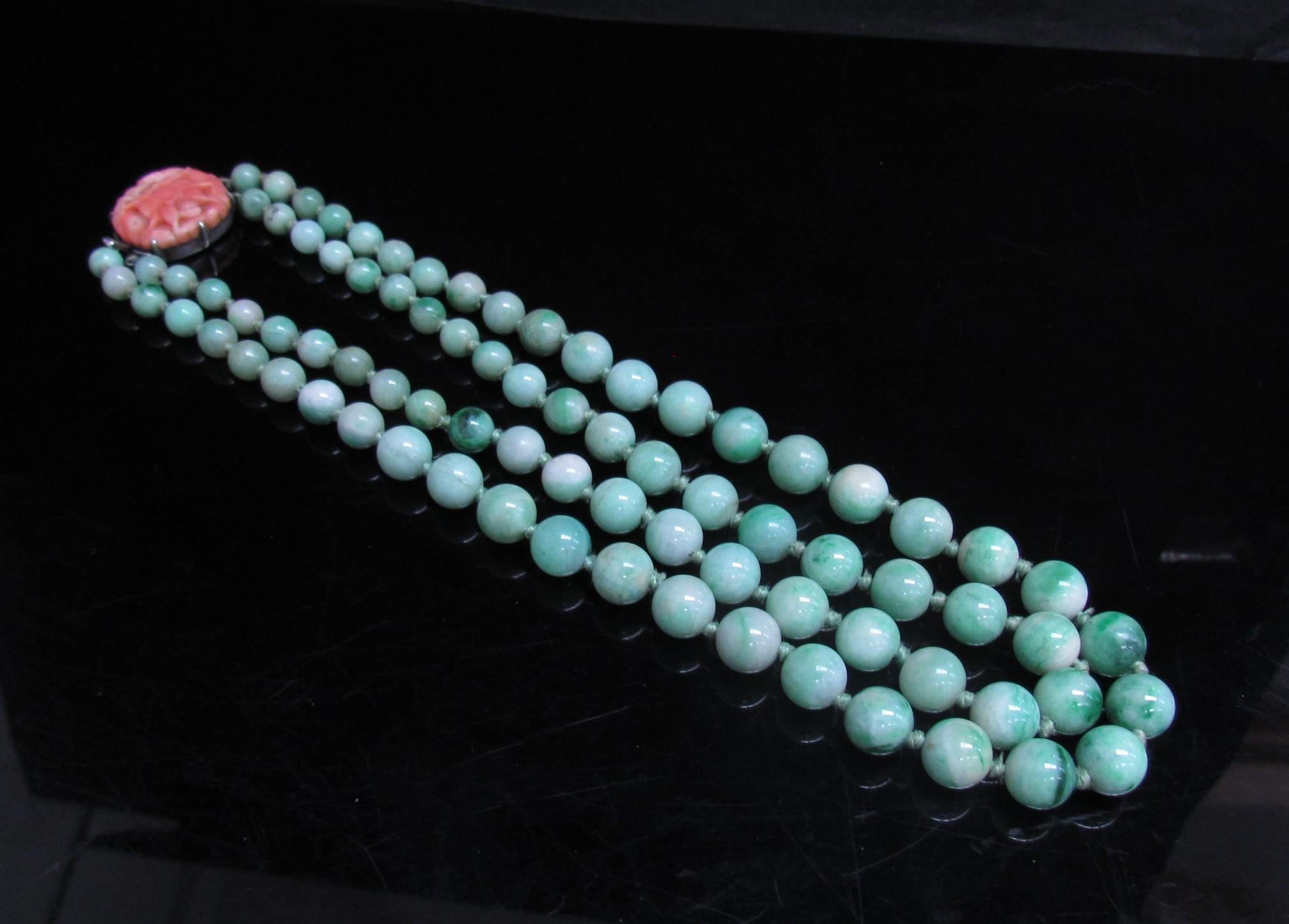 A jade bead necklace with carved coral clasp, 38cm long