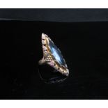A 9ct three tone gold ring set with a large lozenge shaped pale blue stone framed by leaves and