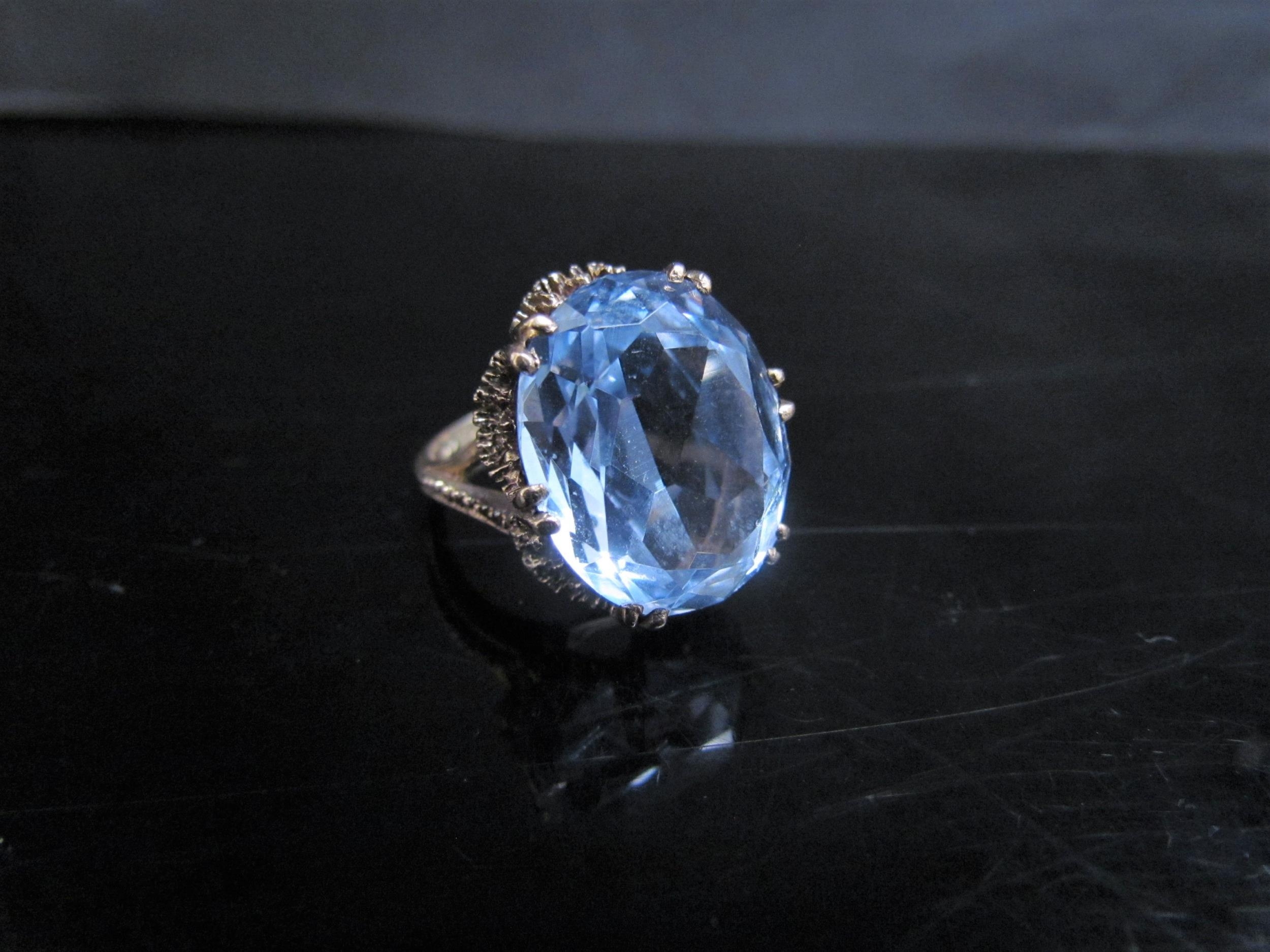 A 9ct gold ring the textured mount set with an oval topaz. Size O, 8g