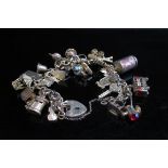 A 9ct gold charm bracelet hung with various charms including London bus, bird in cage, clover