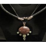 A hardstone pendant set with green and brown stones on leather strap and a woven leather necklace