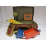 A vintage leather suitcase with mixed toy contents including Meccano motors, tinplate tipping