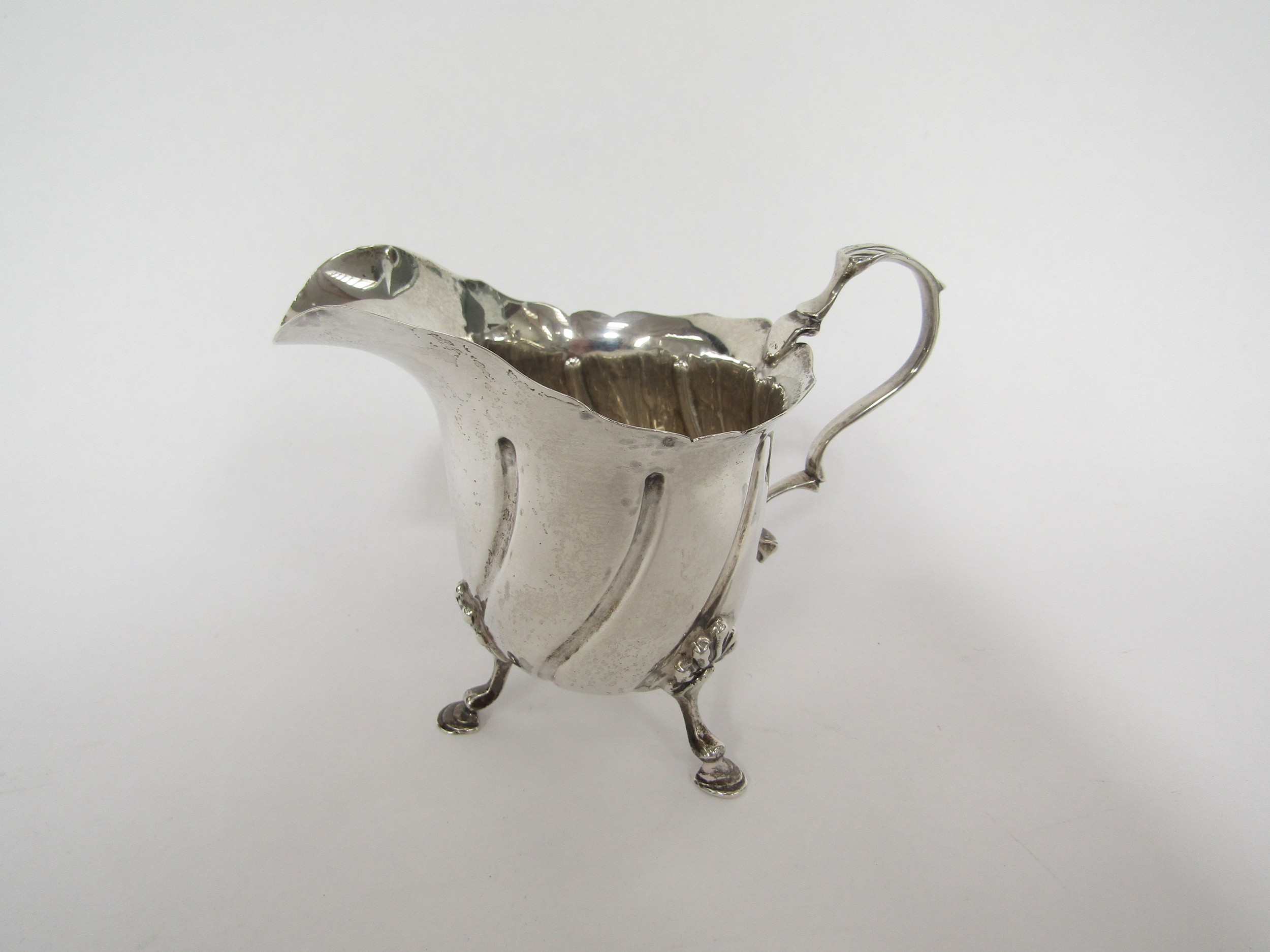 A Nathan Hayes silver cream jug with wrythen ribbed body, shell relief hoof feet, Chester 1899, 128g