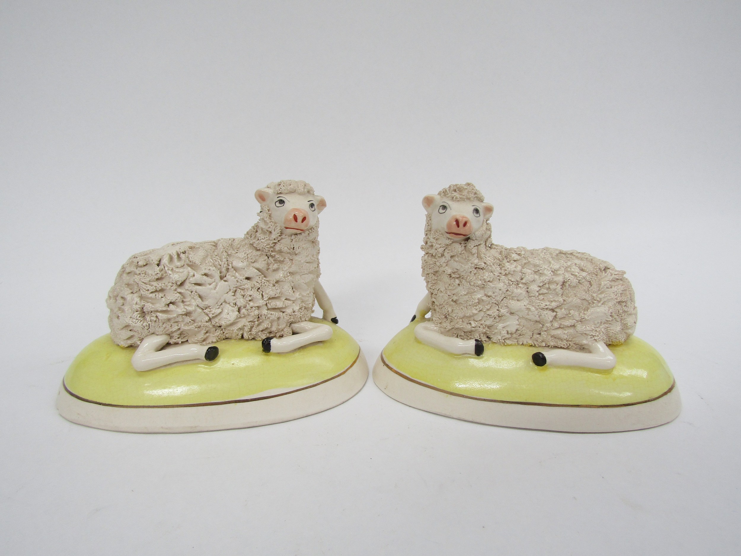 A pair of Staffordshire sheep in yellow domed bases (slight damage), 9cm x 14cm