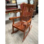 An Indian hardwood rocking chair with carved detail and inlaid arms