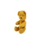 An early 20th Century gold plush teddy bear with humped back, 16cm tall, hard body, moving limbs