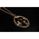 A 9ct gold chain, 46cm long, hung with an Edwardian oval pendant set with garnet and seed pearl,
