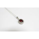 A 9ct white gold garnet and diamond oval pendant hung on chain stamped 375, 45cm long, 2.5g
