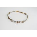 A white and yellow gold bracelet with heart and scroll links set with clear stones, 18cm long, 4.8g