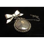A double picture locket framed with paste stones hung on bow brooch backed stamped sterling