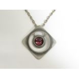 A Bert Larson Danish metal pendant with red stone, signed to reverse, metal chain.