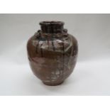 A hand thrown and glazed earthen ware jar with drip glaze design, four lug carrying handles, neck