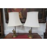 A pair of brass table lamps with lady and gentleman design, cream shades