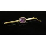 A gold bar brooch set with central Amethyst framed by grey seed pearls, stamped 9ct, 8cm long, 7.5g