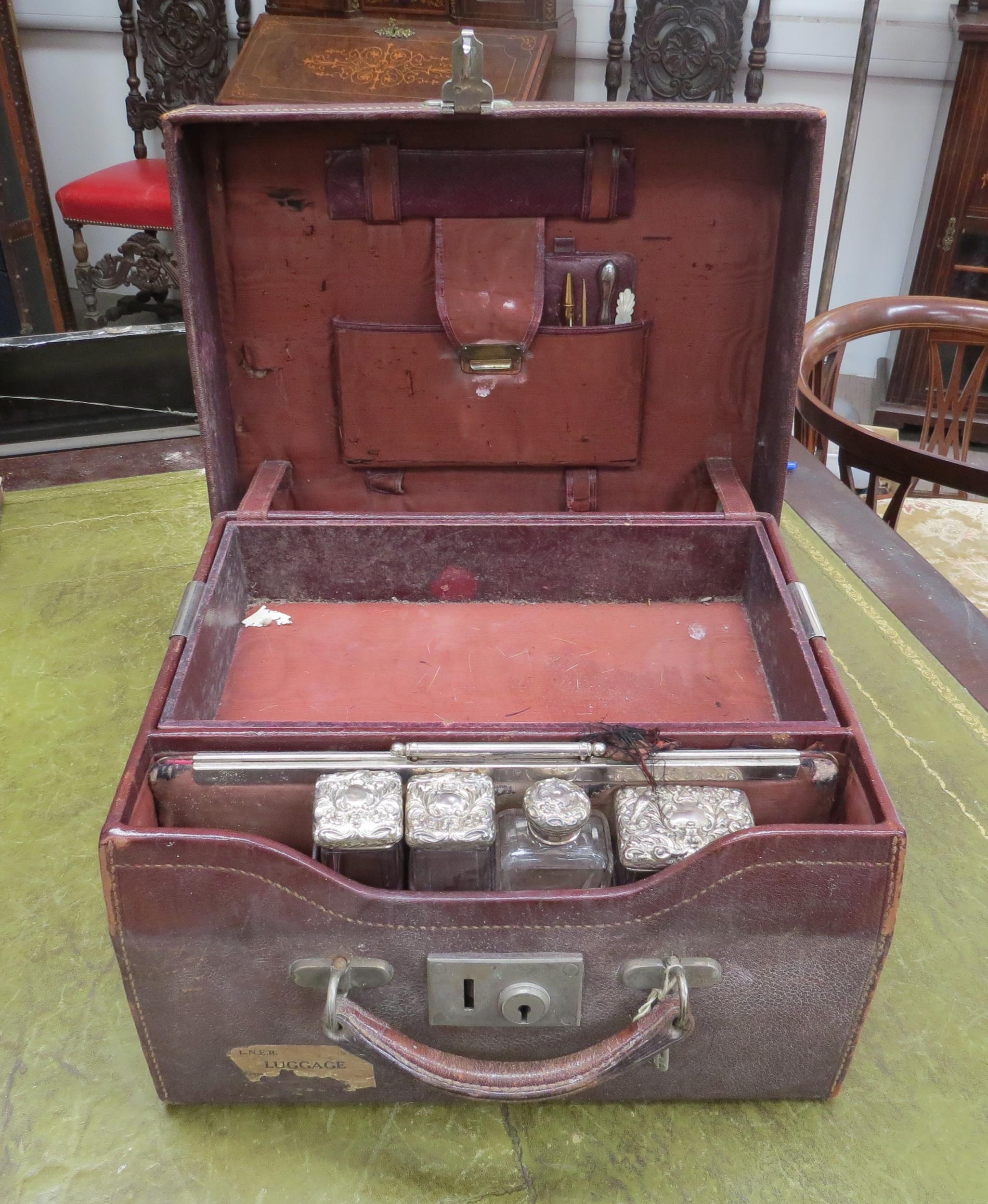 A gentleman's red leather vanity case with part contents including three silver lidded containers by