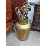 A 19th Century brass churn with twin copper handles, 60cm tall, contents including walking sticks