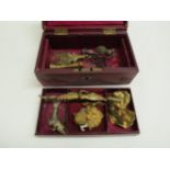 A red leather jewellery box with base metal bijouterie contents including articulated fish, swan