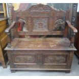 A turn of the 20th Century oak settle/hall seat with carved back, lift up seat to storage space,