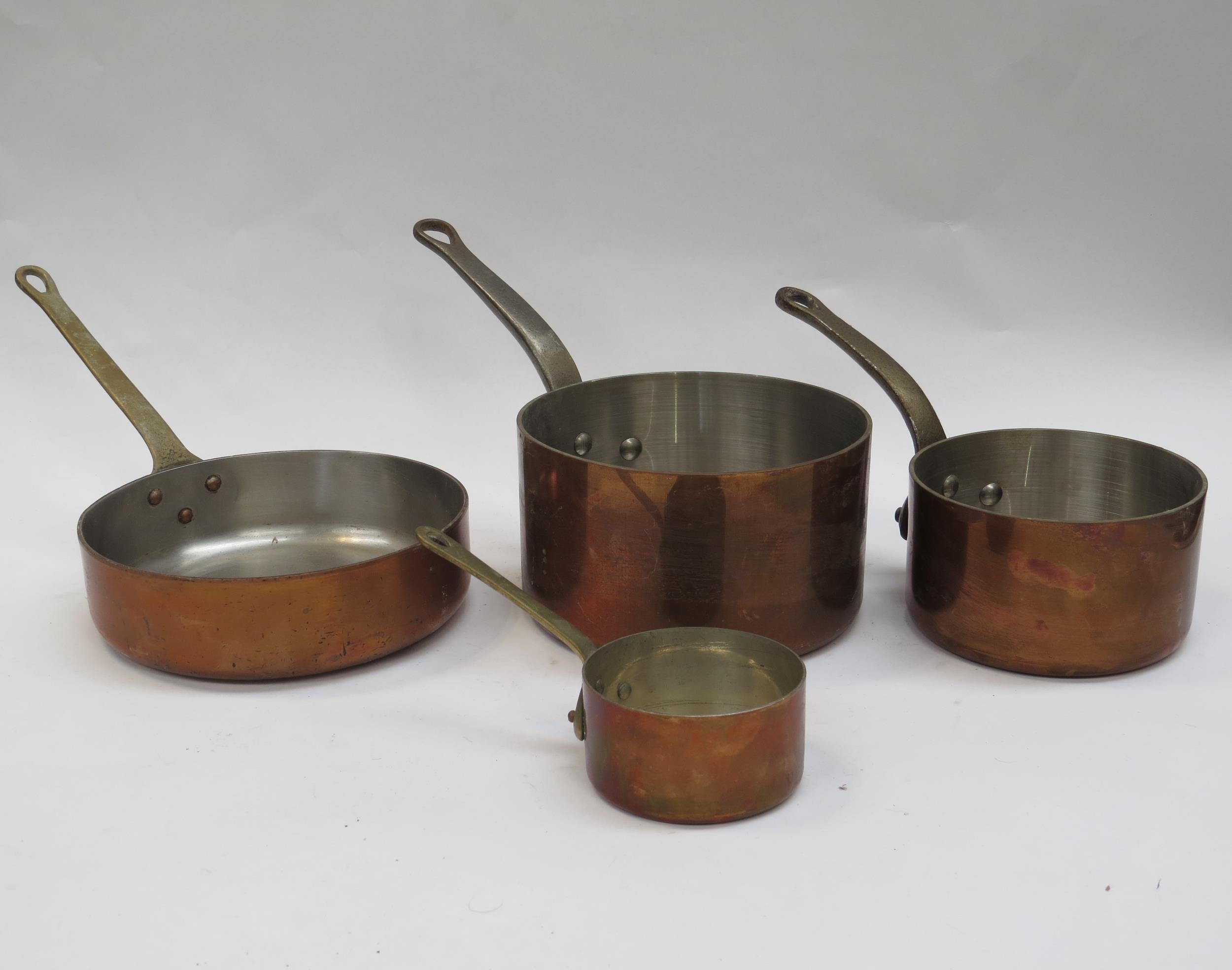 A set of four French copper saucepans of varying sizes with cast metal handles, smallest 9cm