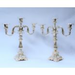A pair of ornate white metal three branch candelabra, 42cm tall