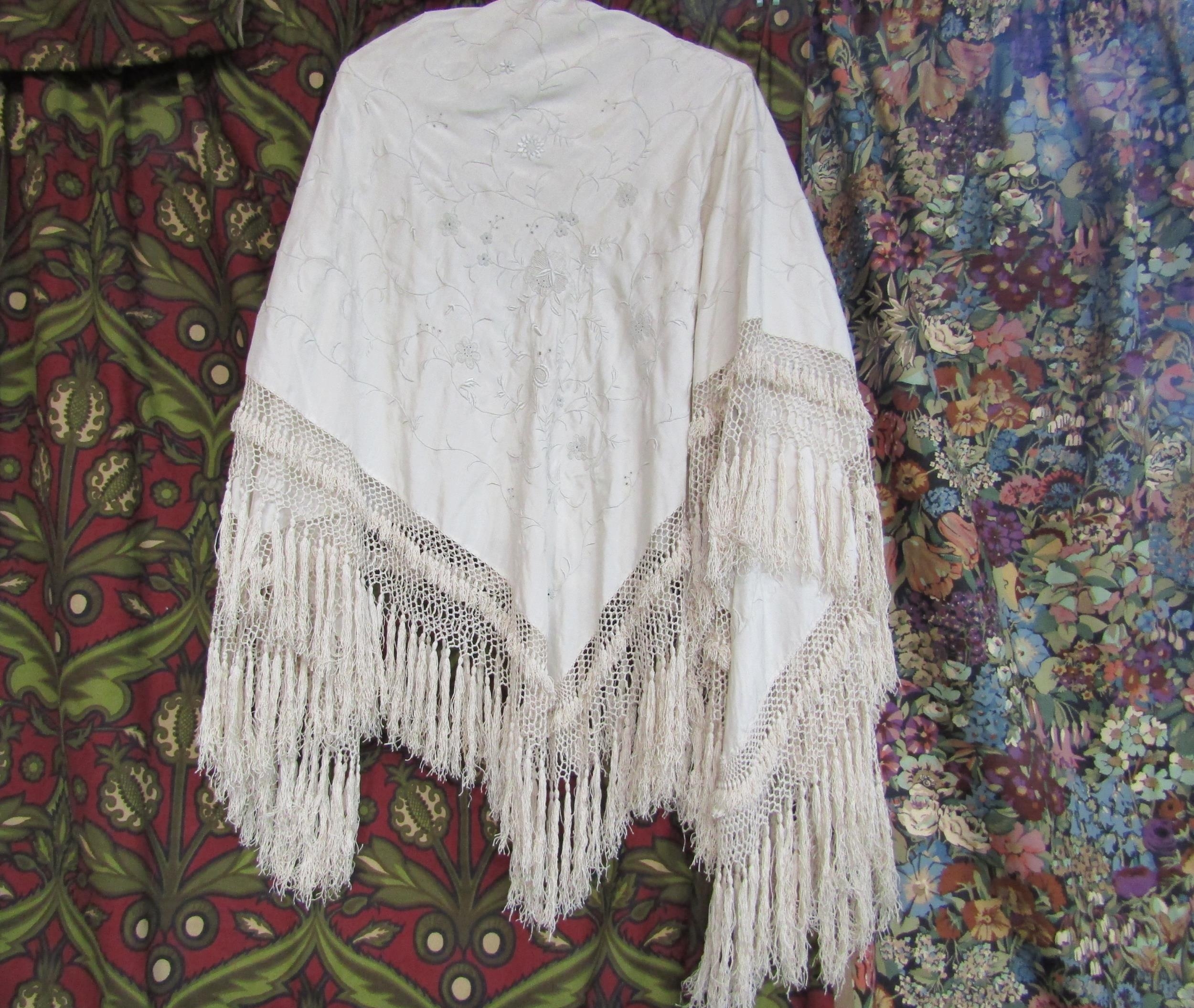 A late 19th/early 20th Century cream silk shawl, embroidered foliate design, deep fringing