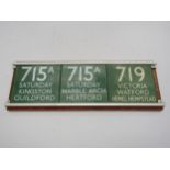 Three enamel bus route plates in wooden display