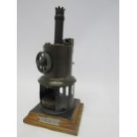 An early 20th Century live steam vertical stationary engine, raised on pine plinth with plaque "